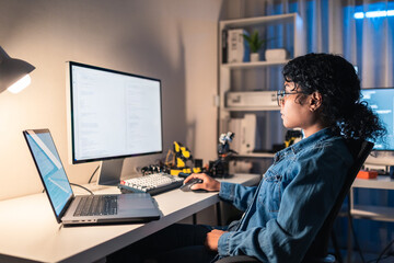 Female engineer coding late at night in her home office, developing AI and robotics system. Concept...