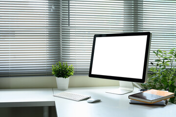 Desktop monitor, wireless keyboard and mouse, and notebooks on white desk