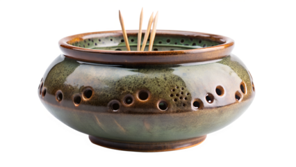 A rustic ceramic incense holder with a green and brown glaze, filled with incense sticks, isolated on transparent background