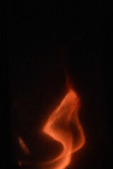 Deep orange s-shape flame in the fireplace with black background