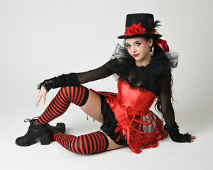 Burlesque circus performer, fantasy female model in halloween jester clown costume with top hat,...