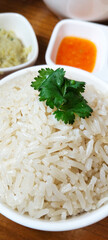 Picture of rice in a white bowl with vegetables sprinkled on top.