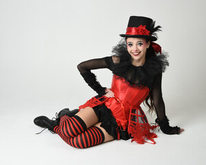 Burlesque circus performer, fantasy female model in halloween jester clown costume with top hat,...