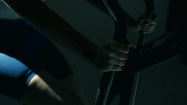 Zbliżenie na dłonie kobiece trzymajace kierownice roweru stacjonarnego w czasie treningu wytrzymalosciowego