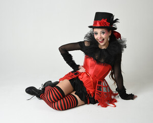 Burlesque circus performer, fantasy female model in halloween jester clown costume with top hat,...