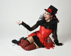 Burlesque circus performer, fantasy female model in halloween jester clown costume with top hat,...