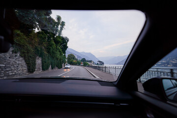 Driving Along Scenic Lake Road with Mountains in the Background