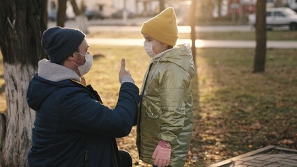 father wears kid mask on his face while walking city park, protect child's body from coronavirus infection, little daughter and dad comply with safety rules of quarantine for going out, happy family.