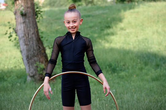 Young gymnast performs a hula hoop routine outdoors, showcasing skill and discipline in a vibrant natural setting. The scene emphasizes athleticism, grace, and dedication to rhythmic gymnastics. - Powered by Adobe