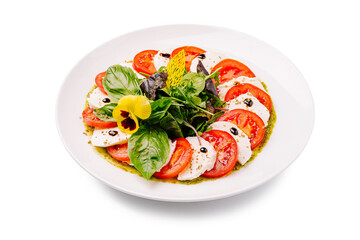 Fresh caprese salad with basil, tomatoes, and mozzarella on a white plate