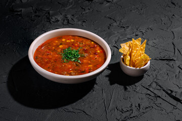 Delicious bowl of spicy soup with fresh toppings and crispy tortilla chips