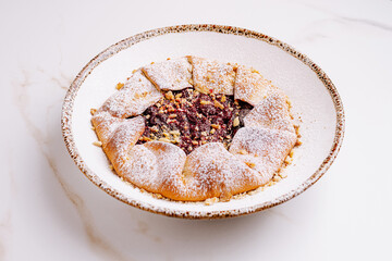 Freshly baked dessert with nuts and powdered sugar on a delicate dish