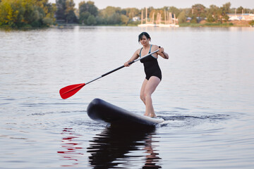 Woman Paddle Boarding on a Calm Lake in the Evening Light