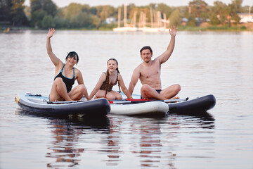 A family of three having fun paddleboarding on a serene lake, creating joyful summer memories...