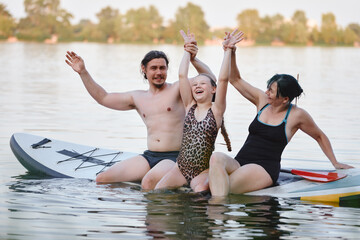 A joyful family bonding together while balancing on a paddleboard surrounded by calm lake scenery.