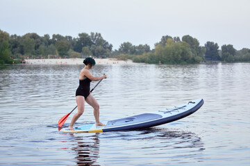 Woman Balance on Paddleboard in Calm Lake with Peaceful Shoreline