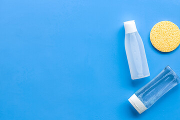 skin care cosmetics with facial tonic, mycelial water and sponge on blue background top view mockup
