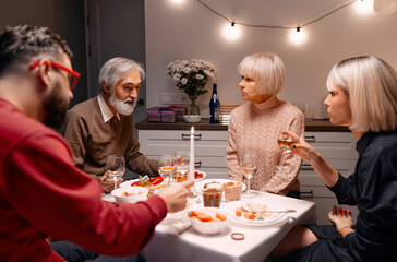 Family group engaging in meaningful conversation around a dinner table in a warmly lit kitchen.