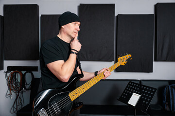 Musician Holding Electric Bass Guitar in Recording Studio With Acoustic Panels