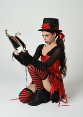 Burlesque circus performer, fantasy female model in halloween clown costume with top hat, red...
