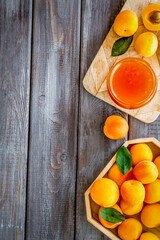 Healthy breakfast. Apricot jam in jar near fresh fruits on dark wooden background top view frame copy space