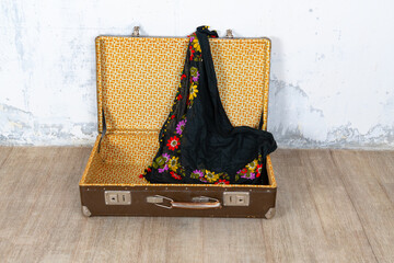 Vintage retro suitcase, the suitcase is open and there is a scarf in it, stand on a stool. The background is a white wall. The concept of retro travel and retro design.