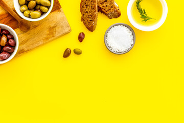 Olives and olive oil in white bowls, top view