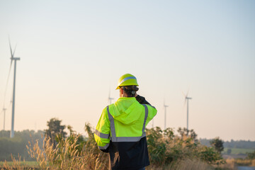 Engineer wearing uniform inspection and survey work in wind turbine farms rotation to generate...