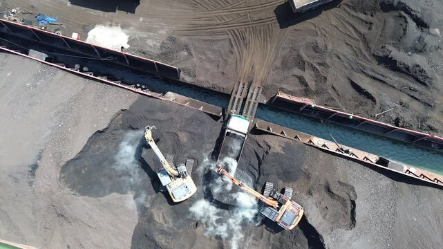 Excavator and Trucks Operating in Coal Stockyard &ndash; Drone Aerial Video
