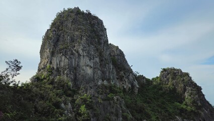 Steep limestone cliff covered with patches of green vegetation and rugged rock formations of Ha...