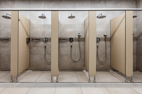 Private shower stalls in a modern tiled communal bathroom facility