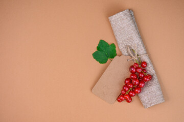 Eco gift tag and red currant on craft background