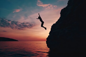 A man is jumping into the ocean from a cliff. The sky is orange and the water is calm