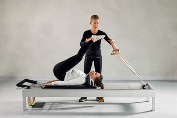 Woman practicing pilates on a reformer with guidance in a fitness studio