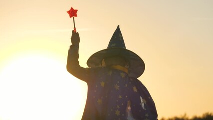boy in a hat conjures magic wand at sunset, halluin, believe in children's magic, kid plays in the glare of the sun, child's carnival costume for holiday, an astranom festive outfit, childhood dream. - Powered by Adobe