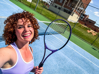 Happy tennis player smiling and holding racket on a sunny court
