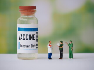 Mini toy of action figure with blurred background. Miniature photography concept design. Minifigure of healthcare crew with vaccine bottle.