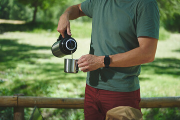Man Pouring Beverage Outdoors in a Scenic Nature Setting