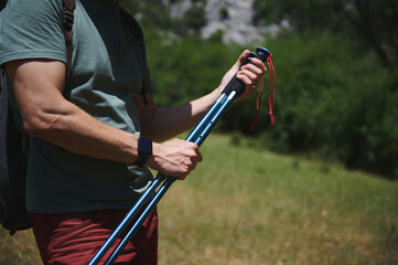 Man Hiking in Mountains Holding Trekking Poles During Summer