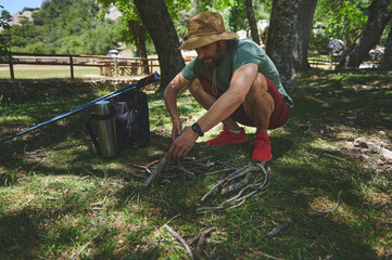 Man Preparing Kindling for a Campfire in a Forest on a Summer Day