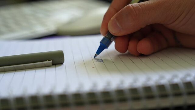 Macro shot of hand writing &ldquo;2026&rdquo; in blue ink on lined notebook&mdash;ideal for new year, planning, or productivity themes.