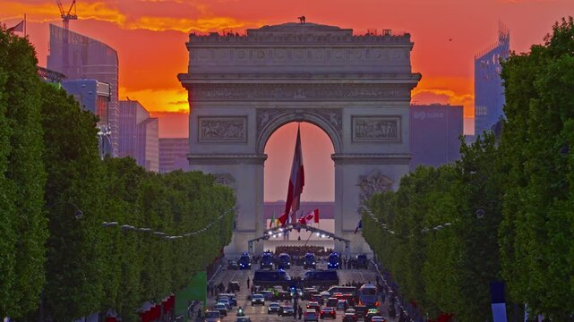 Arc de Triomphe against the backdrop of a beautiful sunset. French flag in the wind in the triumphal arch. Paris, France