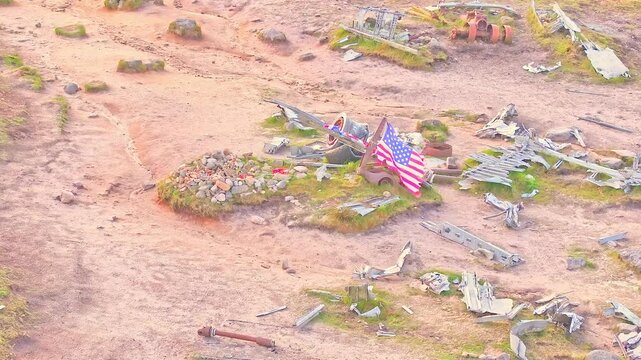 American flag waving in the wind above the memorial stone grave at the B-29 Superfortress WWII plane crash site in the Peak District, England.