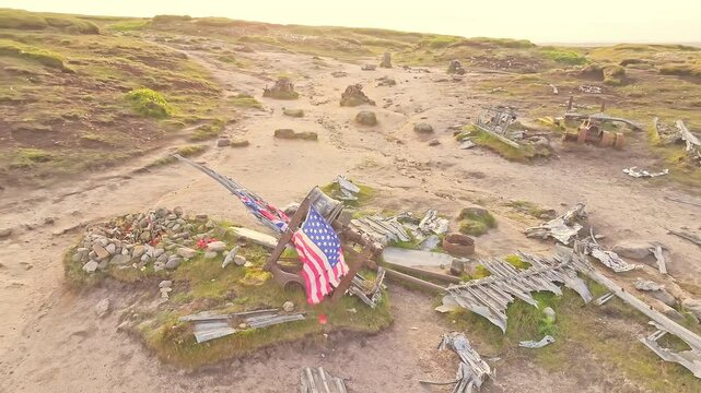 Aerial orbit of stone memorial marking the 1948 B-29 Superfortress plane crash site in the Peak District, England, with American flag waving above.