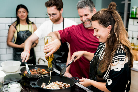 group of young adult friends enjoying a cooking class with a chef, men and women learning to cook
