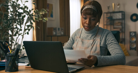 Focused on staying efficient, a young girl uses her work break to reply to delayed messages. She takes notes at her desk to avoid forgetting anything important.