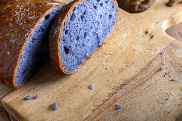 Freshly baked bread with a vibrant purple interior, cooked in blue Thai ancha tea, rests on a...