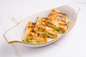 Delicious grilled vegetable rolls served in a white dish on a marble surface