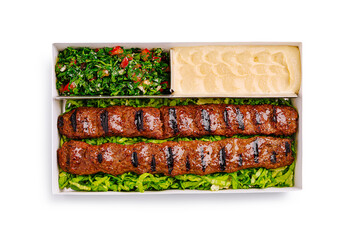Grilled kebabs served with fresh salad and creamy dip in takeout box