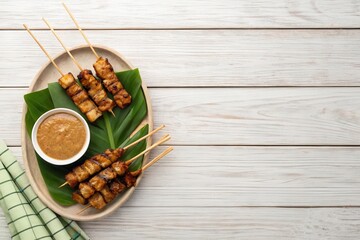 Delicious Satay Skewers on a Rustic Table with Peanut Sauce and Ketupat for a Tasty Meal